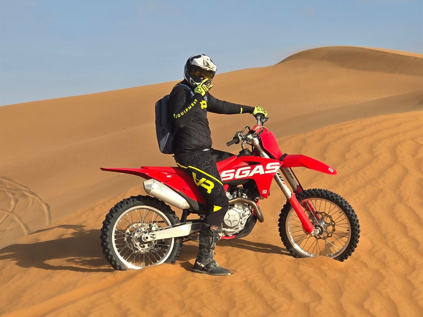 Rider on a red GasGas dirt bike on a desert dune in the UAE