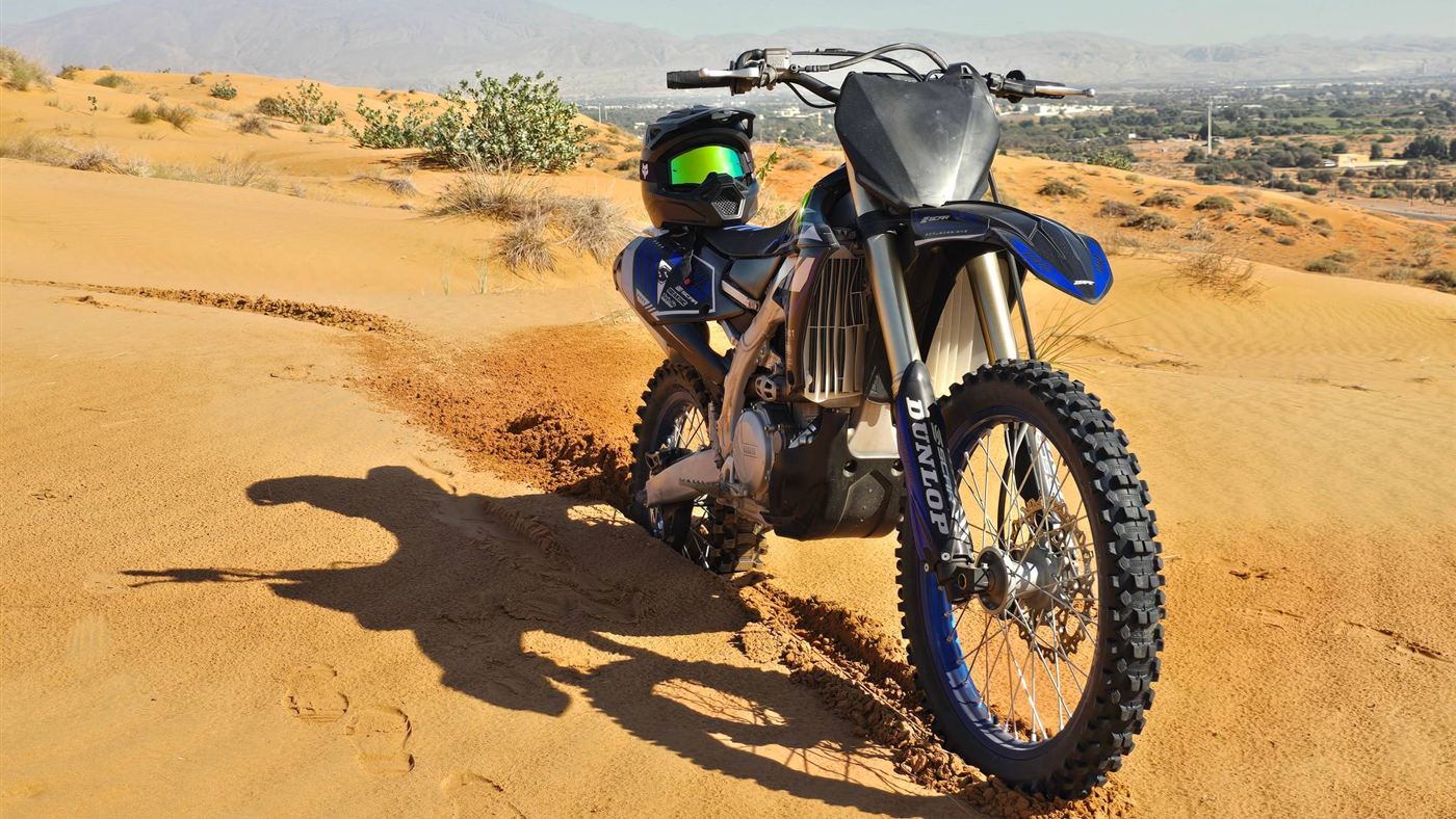 Yamaha dirt bike with its helmet on the seat on a sand dune in Ras Al Khaimah
