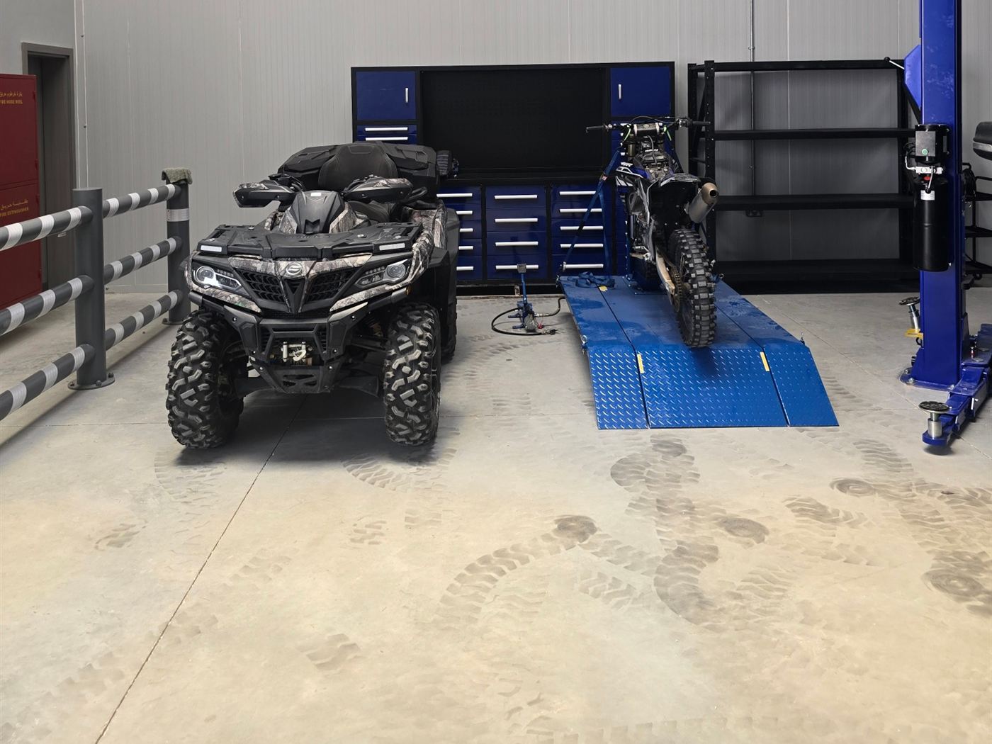 Dirt bike secured on a motorcycle lift next to a quad bike in the Western Auto and Marine workshop