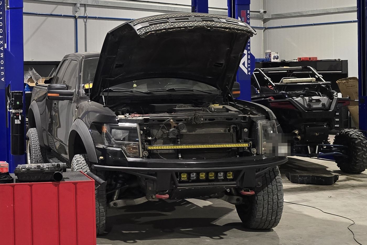 Lifted pickup truck with its hood open and the radiator and engine bay exposed for inspection
