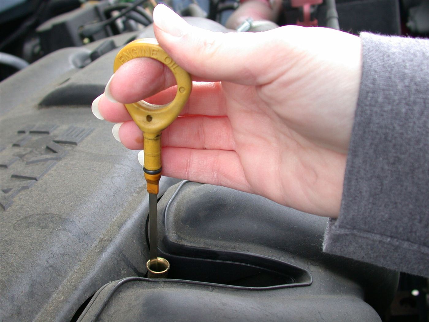 Hand holding an engine oil dipstick to check the oil level