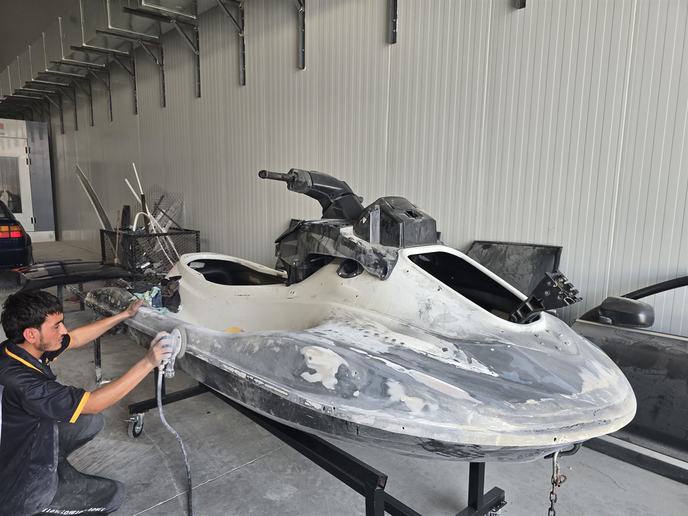Technician sanding and repairing the hull of a jet ski in the Western Auto and Marine workshop