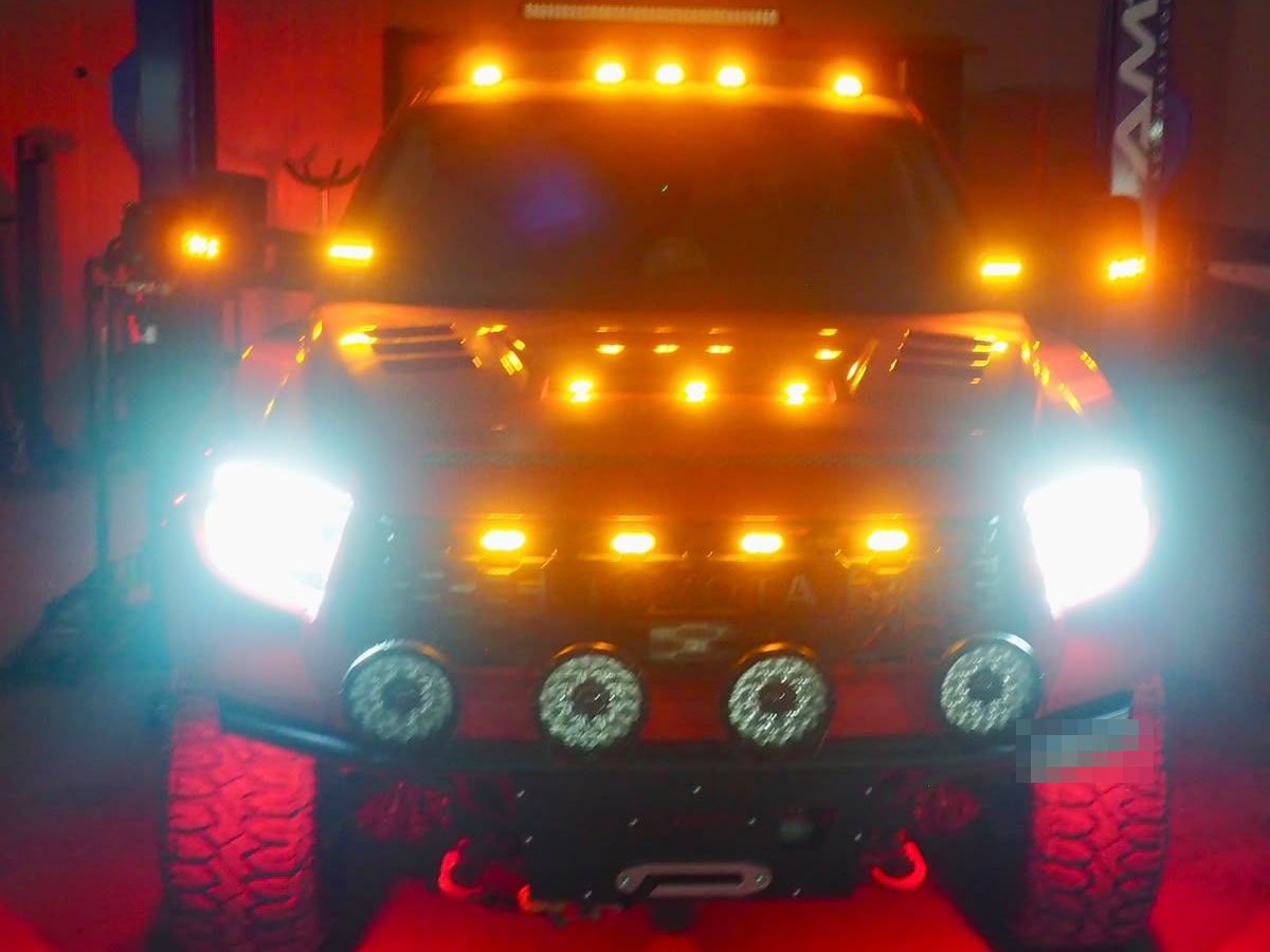 Offroad truck with auxiliary lights and LED bars switched on inside the workshop