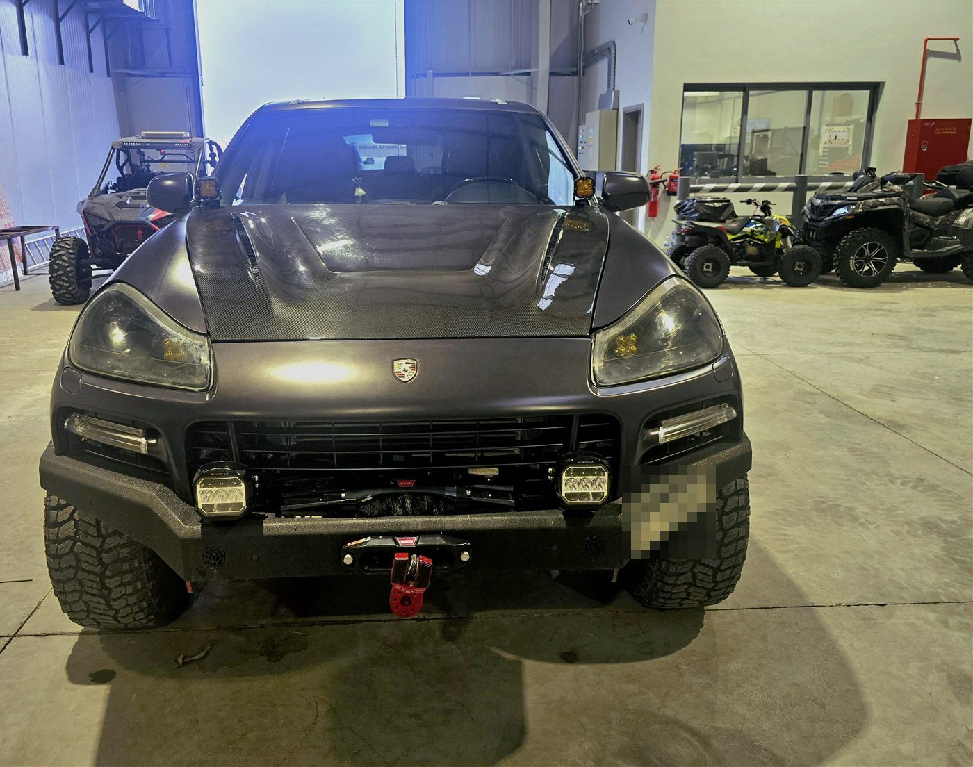 Front of a lifted Porsche Cayenne offroad build with a winch and red recovery shackle on the bumper