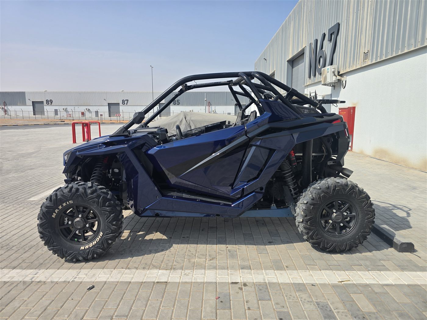 Blue Polaris RZR UTV, side profile, outside the workshop