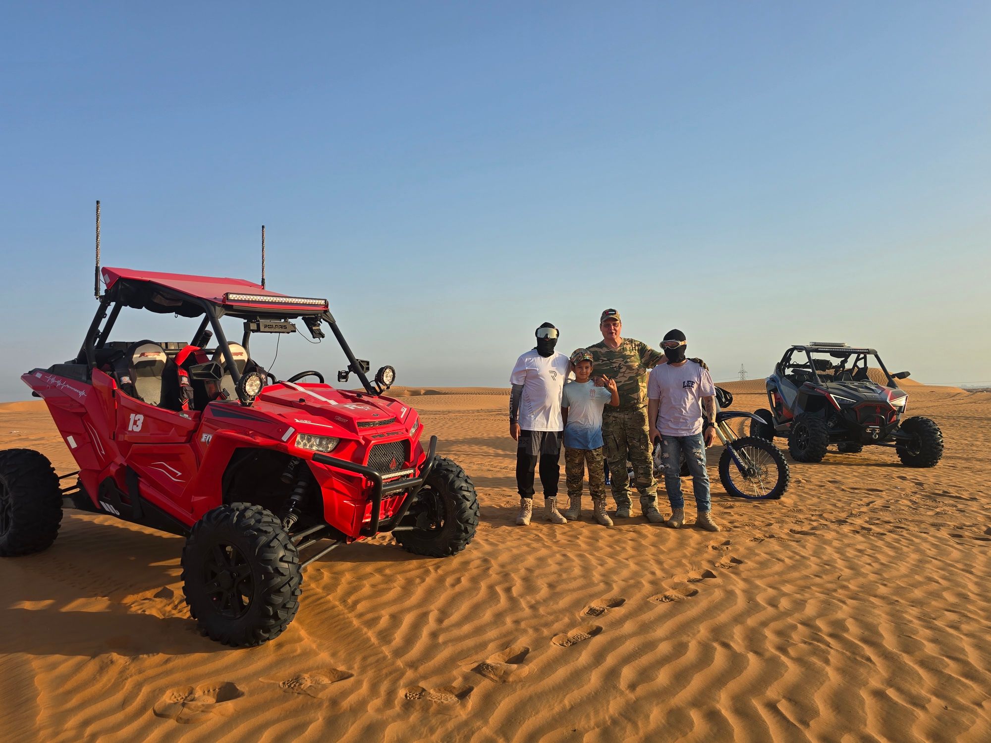 Riders with Polaris side-by-sides and a dirt bike on the desert sand in Ras Al Khaimah