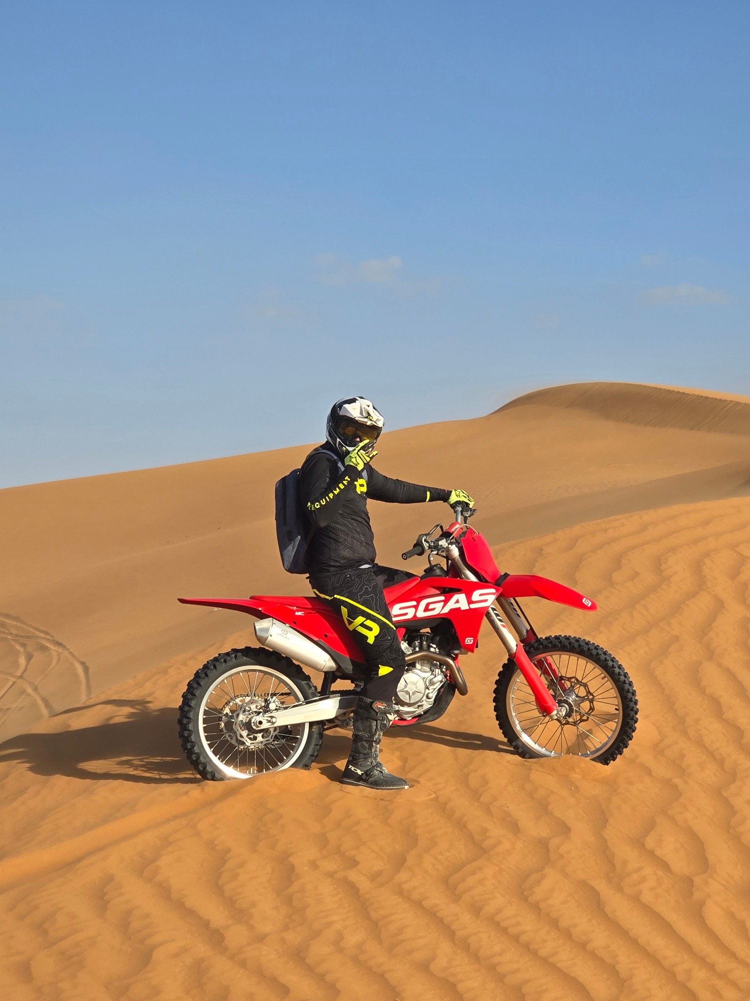 Rider on a red GasGas dirt bike on a desert dune in the UAE