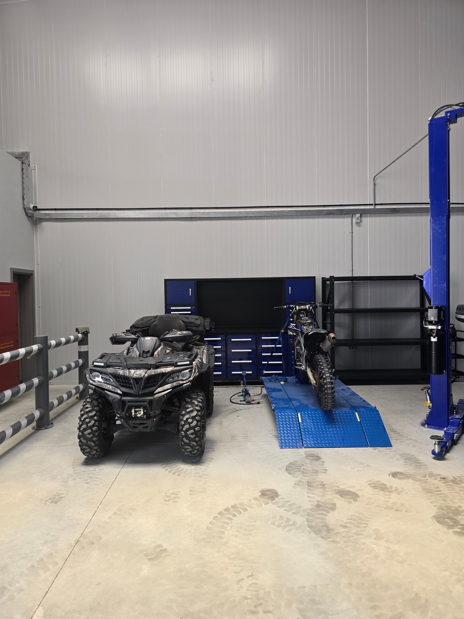 Dirt bike strapped to the motorbike lift next to a quad bike in the Western Auto and Marine workshop, Ras Al Khaimah